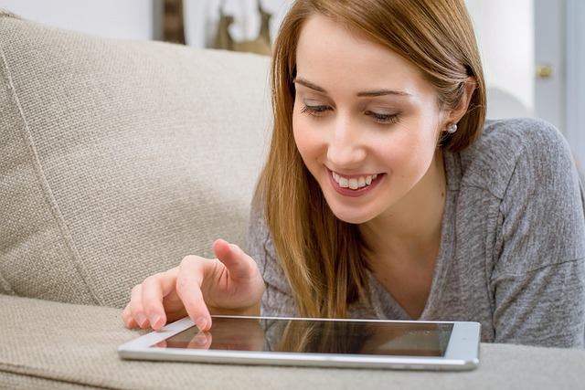 woman-2099466_640 girl on a sofa smiling while she is on her tablet